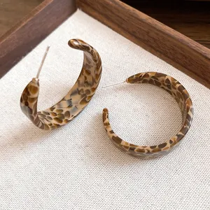 Close-up detail of stylish acetate C-shaped earrings with retro leopard print pattern