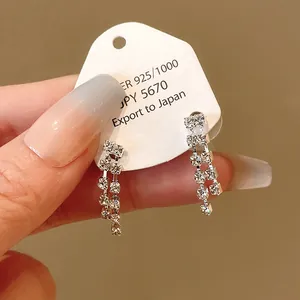 Close-up of elegant rhinestone tassel earrings on white display card