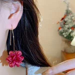 Macro detail of a vintage red floral dangle earring worn on a model's ear for style.