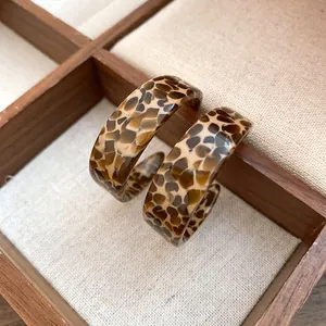 Close-up of leopard print acetate C-shaped hoop earrings with a vintage retro aesthetic