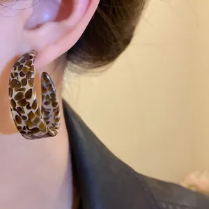 Close-up of tortoise shell acetate C-shape hoop earring worn on ear for women