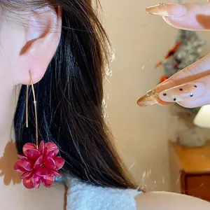 Close-up detail of elegant retro red flower drop earring on model ear for women