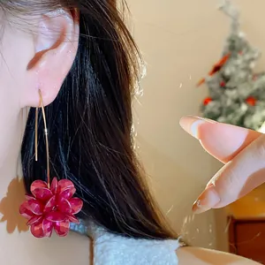 Close-up shot of elegant red flower drop earrings worn by an Asian model in a festive setting