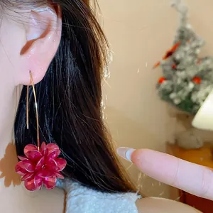 Detailed view of an elegant red vintage flower drop earring worn on a model's ear