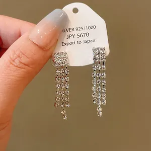 Close-up view of elegant silver rhinestone tassel earrings displayed on a white card
