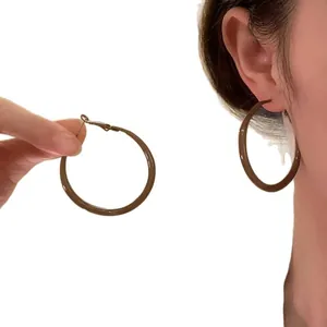 Eleganti orecchini a cerchio vintage in resina marrone scuro su modella e tenuti in mano