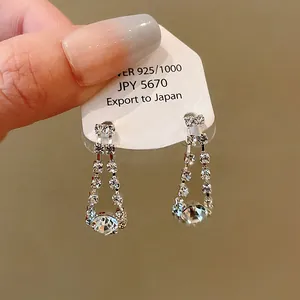 Detailed view of silver tassel earrings with shimmering rhinestones on a tag.