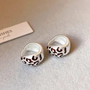 Detaillierte Nahaufnahme von silbernen Retro-Creolen mit braunem Leopardenmuster-Design