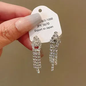 Detailed macro shot of elegant silver rhinestone tassel drop earrings on white tag
