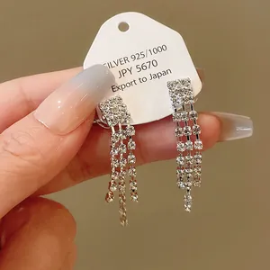 Detail view of sparkly rhinestone tassel dangling earrings on a white display card