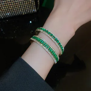 Retro gold-toned open bangle featuring emerald green zircons and white rhinestones