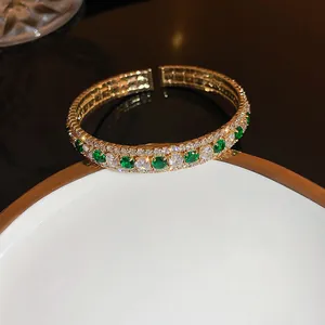 Vintage gold open bangle with emerald green and clear cubic zirconia stones