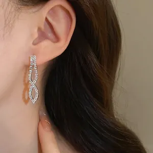 Close-up of elegant silver-toned rhinestone infinity loop dangling earrings worn on ear