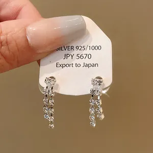 Close-up of elegant silver tassel earrings with sparkly rhinestones on a white card.