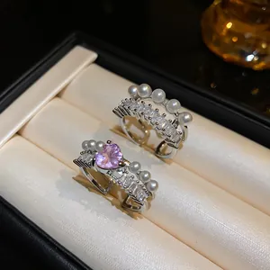Dettaglio di anelli aperti in argento con zircone rosa e perle in una scatola nera