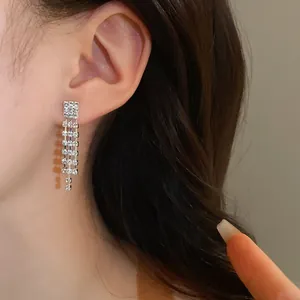 Detailed close-up of sparkling silver rhinestone tassel drop earrings worn on an ear