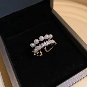 Vista dettagliata di un anello dorato con perle e zirconi in una confezione regalo