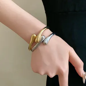 Gros plan de bracelets joncs ouverts en forme de goutte d'eau or et argent minimalistes