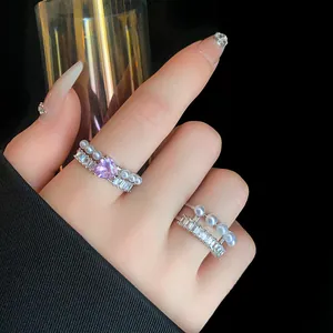 Primo piano di anelli eleganti con perle e zircone a cuore viola sulla mano.