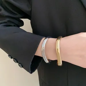 Détail en gros plan de joncs ouverts en forme de goutte d'or et d'argent sur le poignet