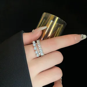 Dettaglio di un elegante anello a due strati con zirconi baguette e perle bianche