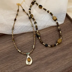 Detail view of Maillard style necklace with irregular tiger eye stones and gold pendant.