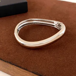 Détail d'un bracelet jonc en métal argenté poli en forme de goutte avec charnière
