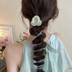 Detail view of a green rose hair clip and spiral hair tie on a bubble braid hairstyle.