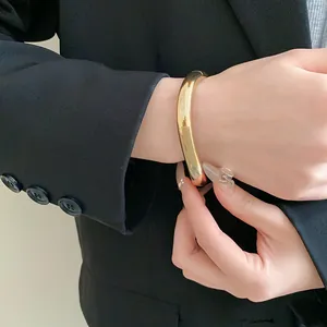 Vue détaillée d'un bracelet jonc doré en forme de goutte au poignet d'un mannequin