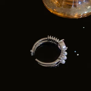 Dettaglio laterale di anello aperto argento con cuore rosa e piccole perle