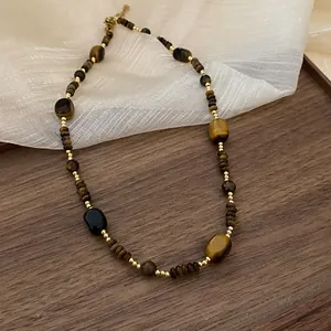 Detail view of a handcrafted irregular tiger eye stone necklace with golden beads