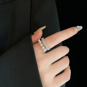 Dettaglio di un anello a doppio strato con eleganti perle e zirconi baguette