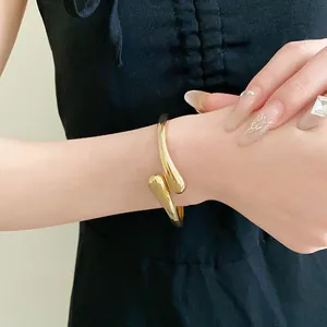 Vue détaillée d'un élégant bracelet jonc doré en forme de goutte d'eau brillante