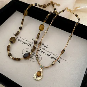 Macro detail of irregular tiger eye stone beads and gold accents on a niche fashion necklace