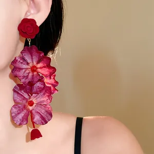 Close-up of elegant floral drop earrings with red flocked roses and purple silk petals