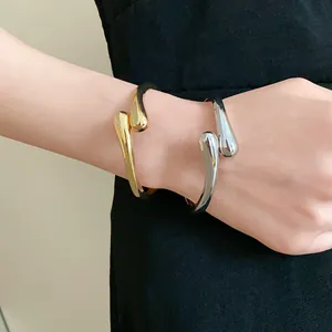 Vue détaillée de joncs ouverts minimalistes en forme de goutte d'eau or et argent