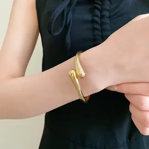 Gros plan sur un élégant bracelet jonc doré ouvert en forme de goutte d'eau chic