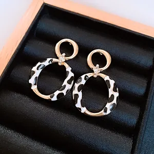 Detail view of gold-tone hoop earrings with black and white animal print enamel