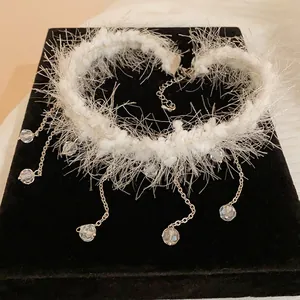 Macro detail of a white fuzzy choker necklace featuring dangling crystal tassel charms.