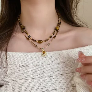 Close-up of layered necklace featuring irregular tiger eye stones and Maillard tones.