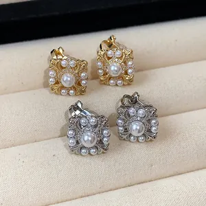 Nahaufnahme von Vintage-Perlenohrclips mit filigranem Lilienmuster in Gold und Silber