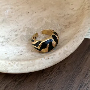 Detailaufnahme eines Vintage-Goldrings mit unregelmäßigem schwarzem Emaillemuster.