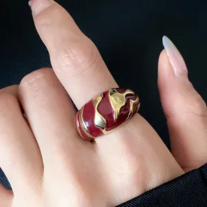 Nahaufnahme eines Vintage-Rings in Goldoptik mit roten Emaille-Wellenmustern am Finger