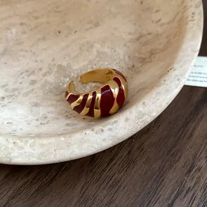 Nahaufnahme eines goldenen Vintage-Rings mit unregelmäßiger roter Emaille-Struktur