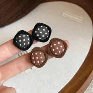 Detailed macro view of vintage fabric polka dot stud earrings in black and brown colors
