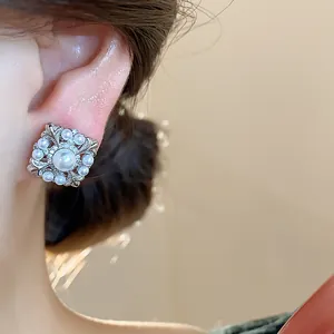 Detailaufnahme des silberfarbenen Iris-Blumen-Perlen-Ohrclips am Ohr eines Modells