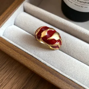 Nahaufnahme eines Vintage Goldrings mit unregelmäßiger roter Emaille Textur in einer Box