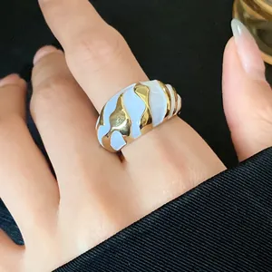 Detailansicht eines Vintage-Metallrings mit einzigartigem gold-weißem, unregelmäßigem Emaille-Muster.