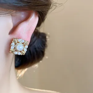Makro-Detail von luxuriösen 18k vergoldeten Iris-Perlen-Ohrclips an einem Model