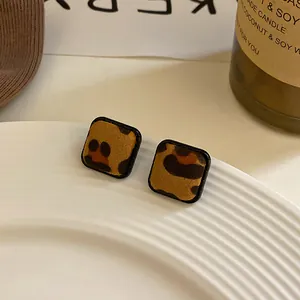 Detalle macro de pendientes cuadrados con estampado de leopardo y marcos negros simples